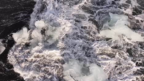 Chunks of ice floating in dark waves on Diamond Beach, Iceland, from above