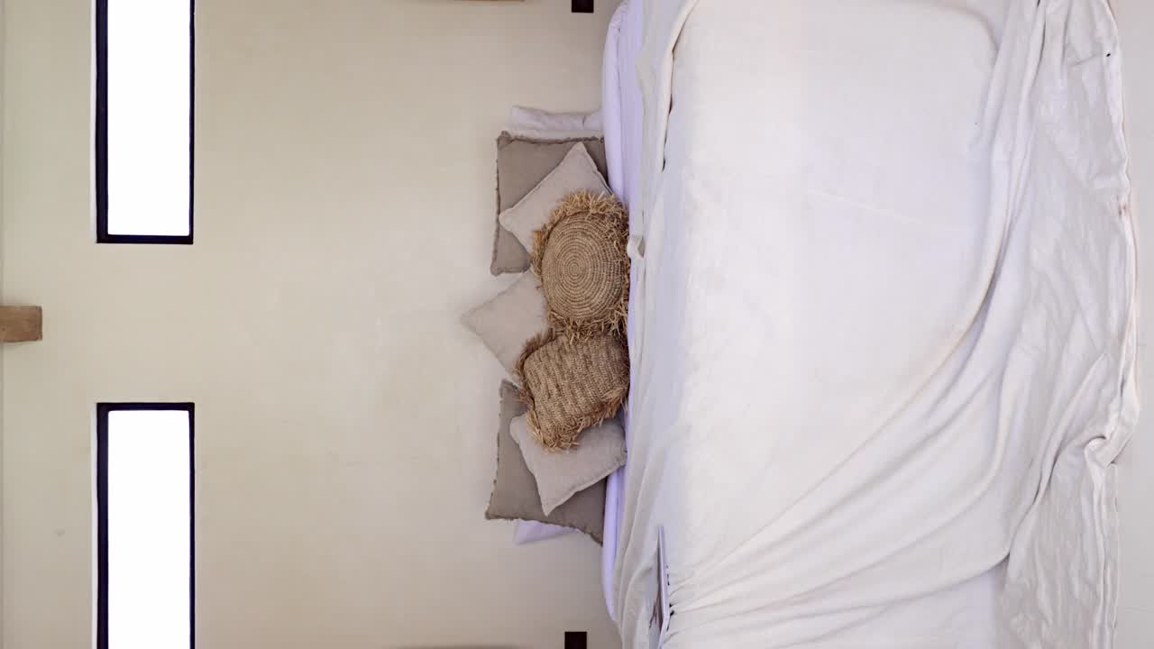 detalles de la decoración de la habitación desordenada en el dormitorio de la villa boho - lanzar cojines, mesita de noche de madera y lámpara colgante - disparo revelador vertical