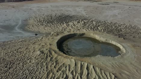 aerial circle dolly around mud volcano with mud pool in crater