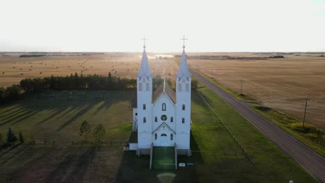 frontal aerial view of roman catholic church in north american prairie during sunset