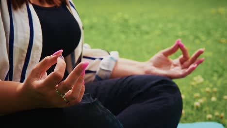 woman practicing meditation outdoors with hands in mudra position on a yoga mat in nature