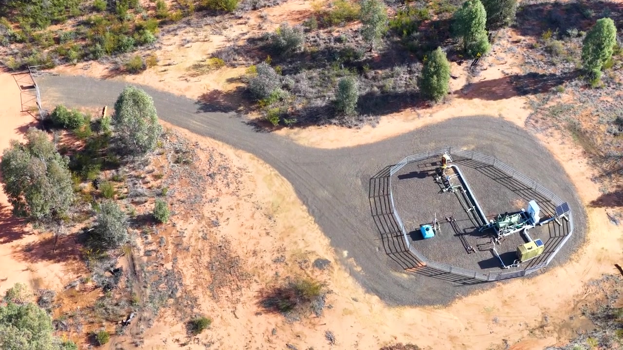 Aerial view drifting over an isolated natural gas extraction well in the Australian Pilliga bushland.