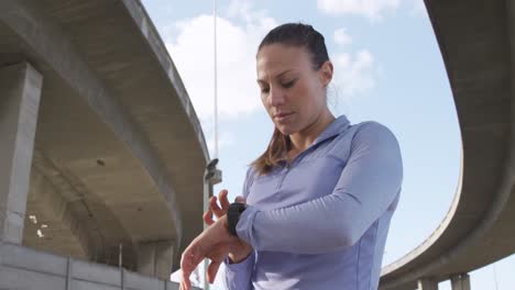 mujer caucásica deportiva comprobando su reloj inteligente al aire libre