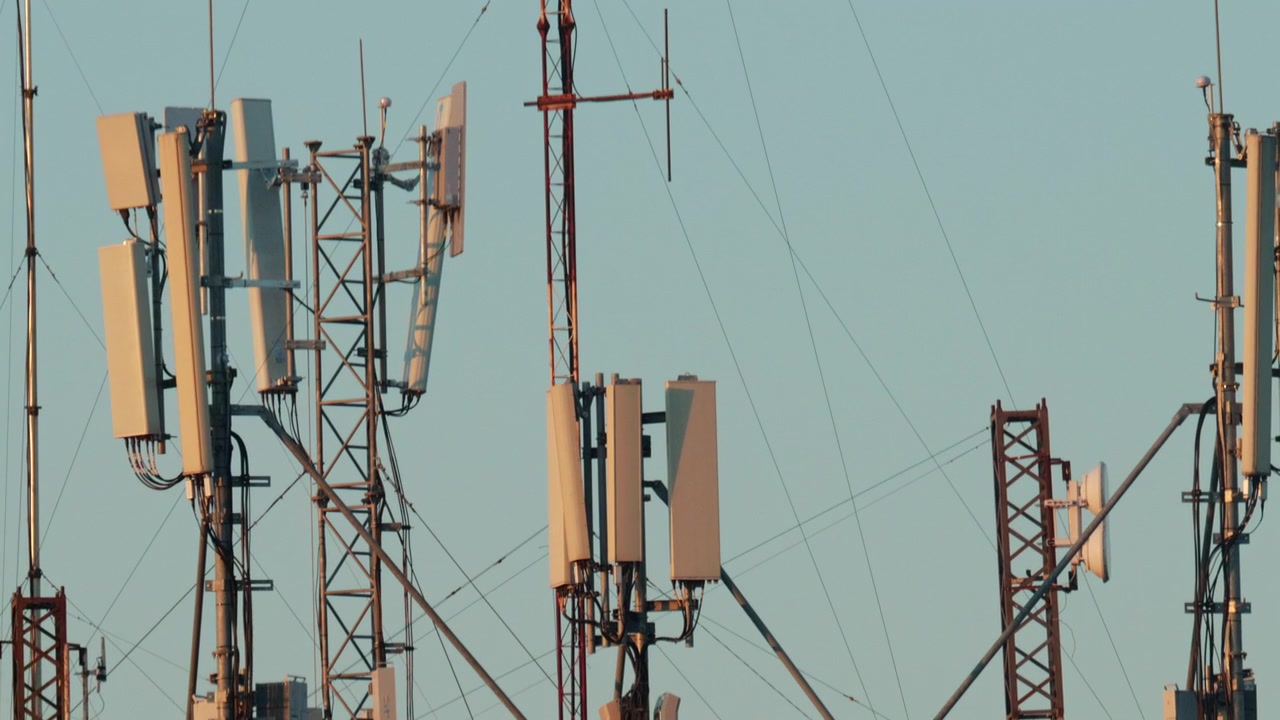 Close up of a telecommunications antenna mounted on a metal tower structure against a clear blue sky