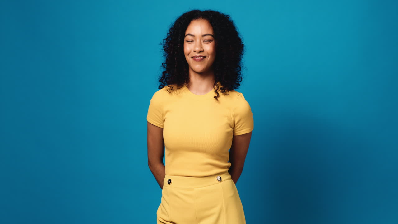 Woman in Yellow Outfit Posing in Front of Blue Background