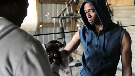 coach tying hand wrap to a boxer in the gym