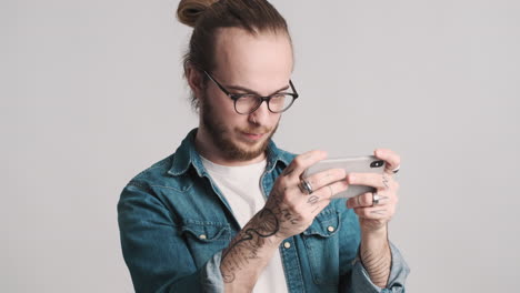 caucasian young man playing video games on smartphone.