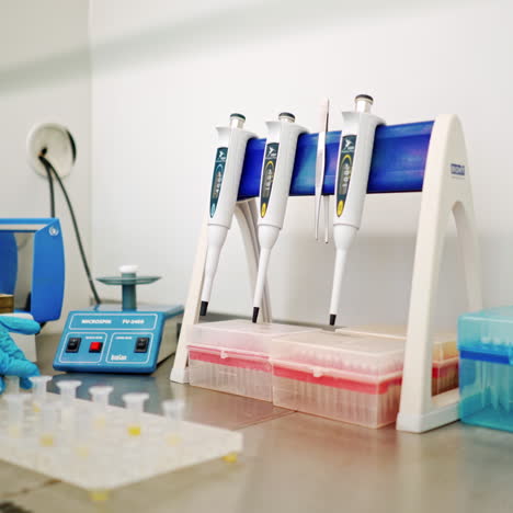 hand of medical worker checking vials of liquid. female's hand in sterile glove putting test tubes one by one into special machine in lab.