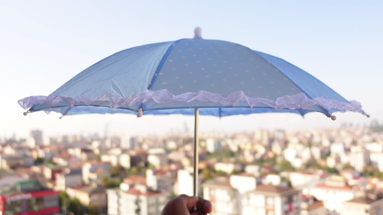 светло-голубой зонтик с точками над городским пейзажем