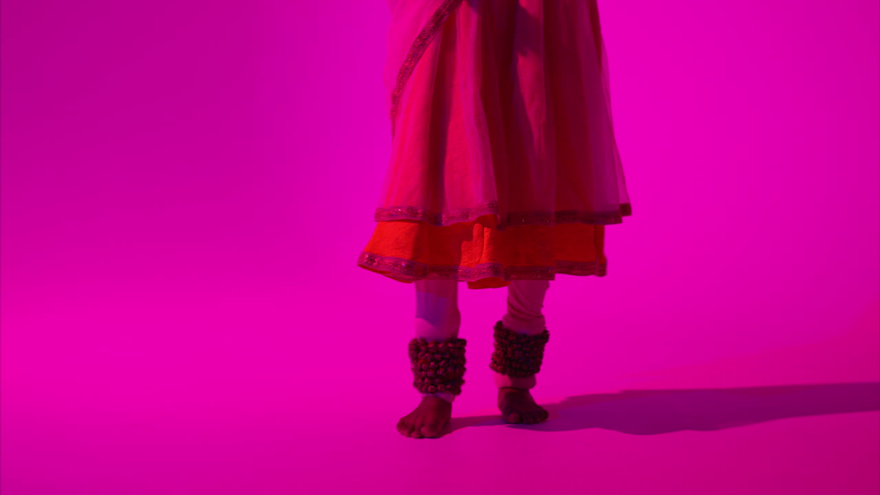 cerca de los pies y las campanas de la bailarina de kathak femenina que realiza el baile vestida con el vestido tradicional indio contra un fondo púrpura 10