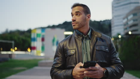 Young-man-using-smartphone-and-walking-outdoors.