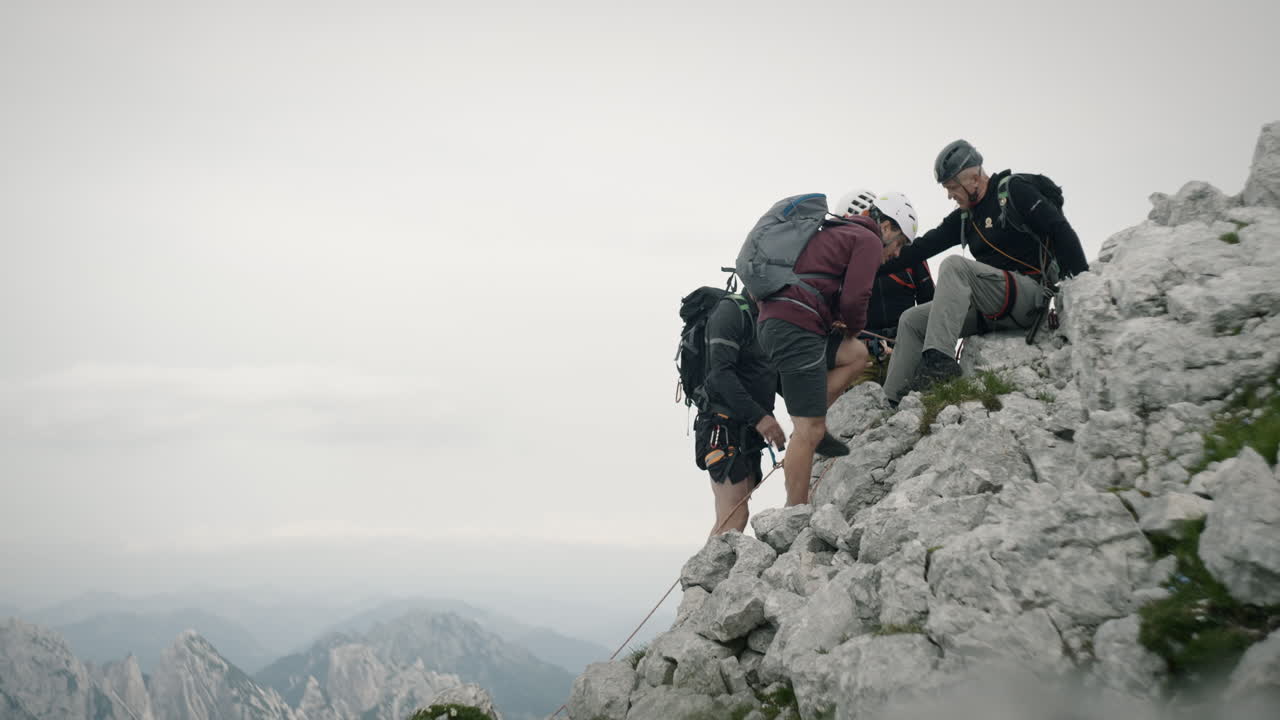 un grupo de excursionistas se detiene para descansar en la roca en las montañas, usando un equipo de escalada completo
