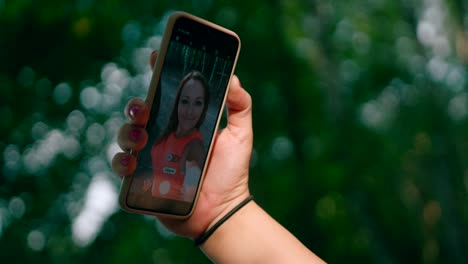 Eine-Glückliche-Frau,-Die-Selfie-fotos-Mit-Einem-Handy-Mit-Einem-Abstrakten-Blick-Auf-Einen-Grünen-Wald-Im-Hintergrund-Macht