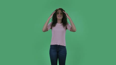 portrait of beautiful african american young sick woman is looking at camera. she has temperature and cough. burning brunette with wavy hair in jeans and a beige blouse on a green screen in the studio. health protection corona virus concept. slow motion