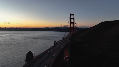 aerial of golden gate bridge and silhouette of mountain at dawn, with a calm bay