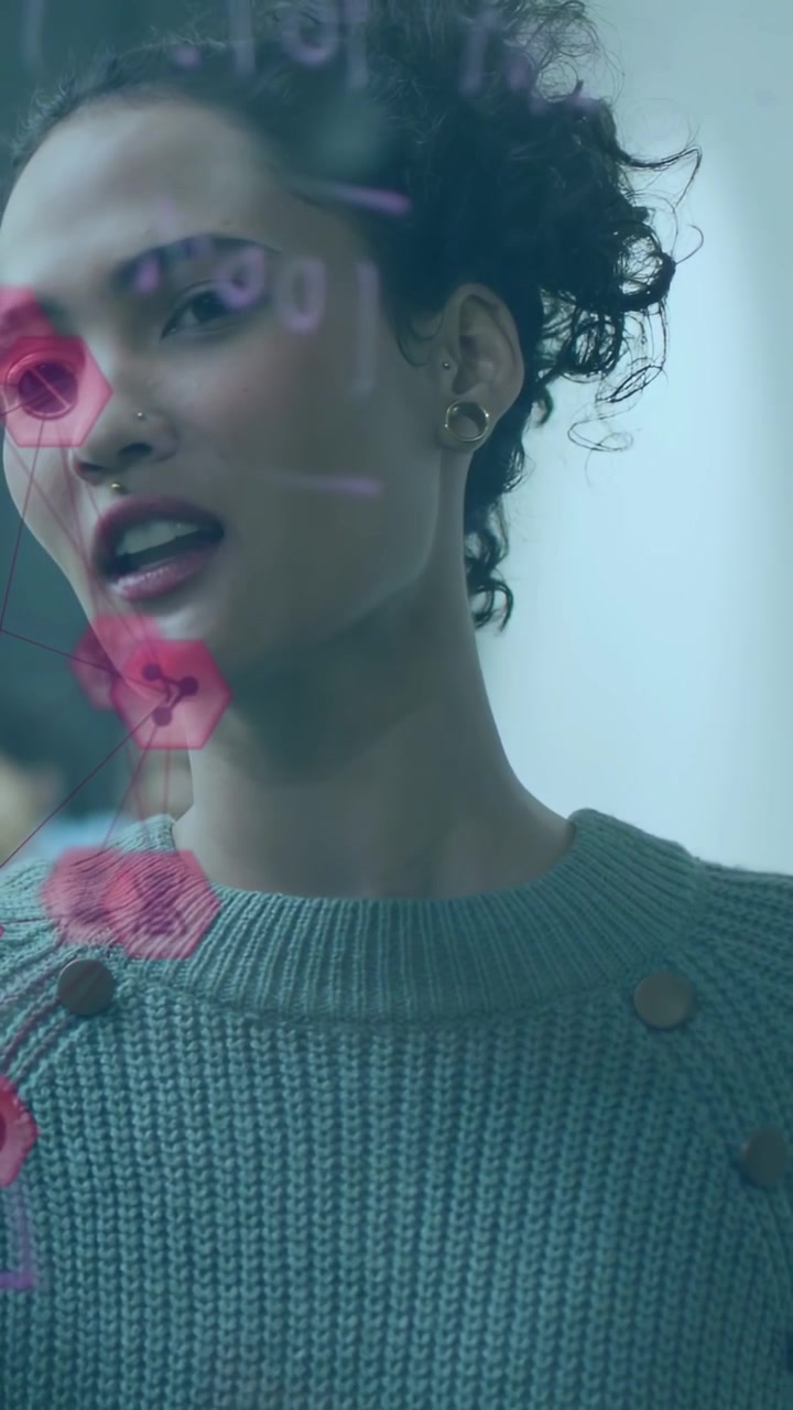 Video verticale: Donna che presenta un piano girandosi verso il team in una riunione di lavoro, con icone esagonali rosa su vetro