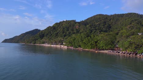 amazing aerial top view flight beach village huts resort, tropical bungalows on mountainous island thailand 2022