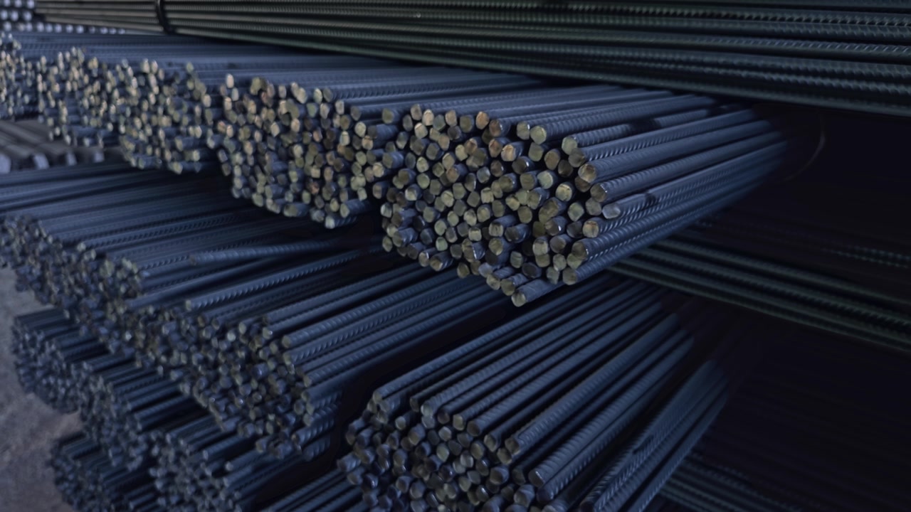 Fasci di tondini d'acciaio impilati in un magazzino industriale, pronti per applicazioni di costruzione e rinforzo. - primo piano