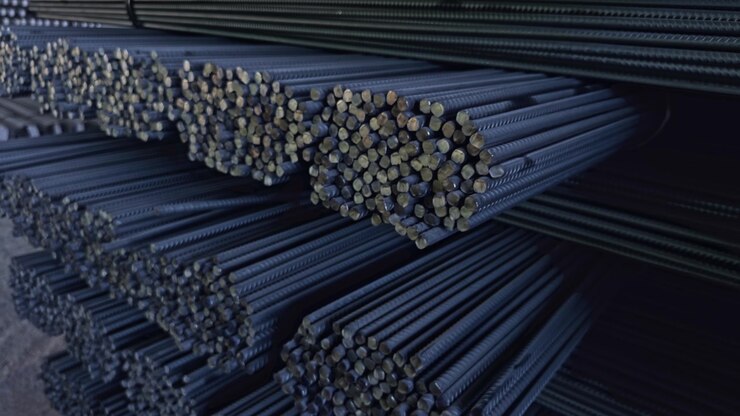 Fasci di tondini d'acciaio impilati in un magazzino industriale, pronti per applicazioni di costruzione e rinforzo. - primo piano