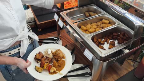 woman serving herself at a buffet with various food options.