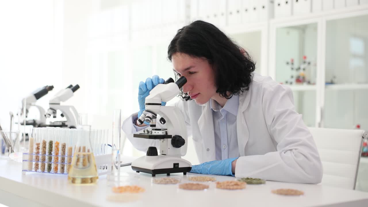 Scientist Examining Samples Under Microscope in Lab