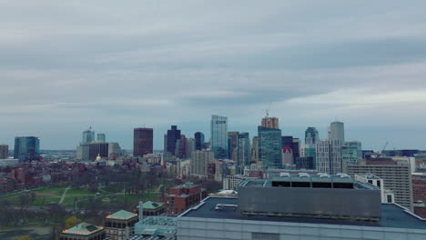 Aerial-panoramic-view-of-modern-tall-buildings-in-city-centre-at-dusk.-Sliding-reveal-of-public-park.-Boston,-USA