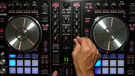 dj mixing music with digital controller turning knobs overhead party