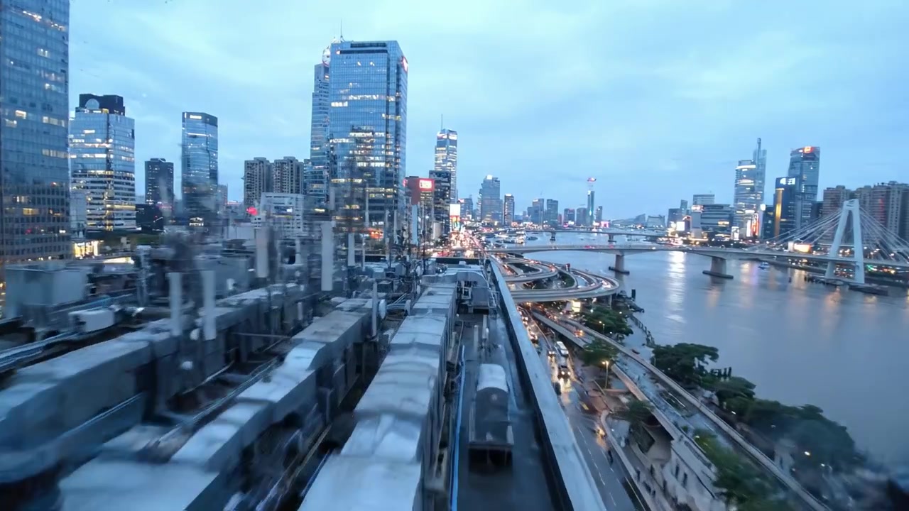 現代的な都市環境における、夕暮れ時の活気ある都市生活を捉えた魅惑的な都市景観の移り変わり。ダイナミックな光、交通の流れ、そして美しい川の眺めが特徴。