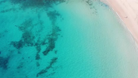 Birds-Eye-View-Over-Beautiful-Blue-Turquoise-Ocean-Waters-Beside-Idyllic-Beach