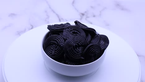 black licorice candies on white marble background