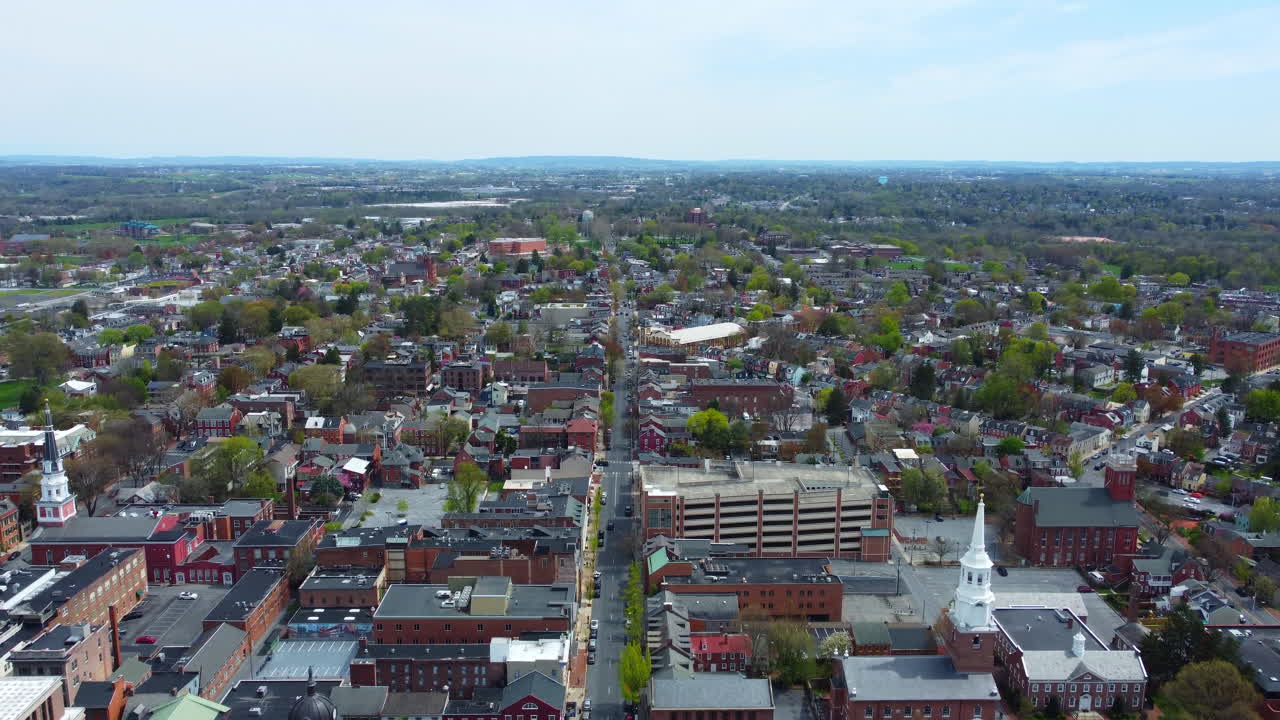 A captivating aerial journey over Lancaster City, Pennsylvania in spring, showcasing architecture, tree-lined streets, blooming flowers, and a lively downtown with urban charm from a drone’s vantage.