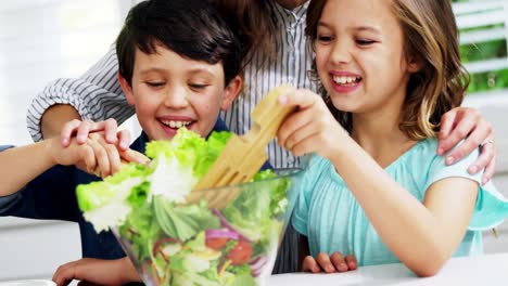 familia feliz preparando ensalada de verduras