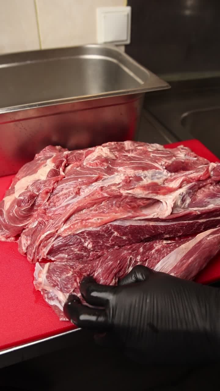 Butcher Cutting Raw Meat on a Red Cutting Board