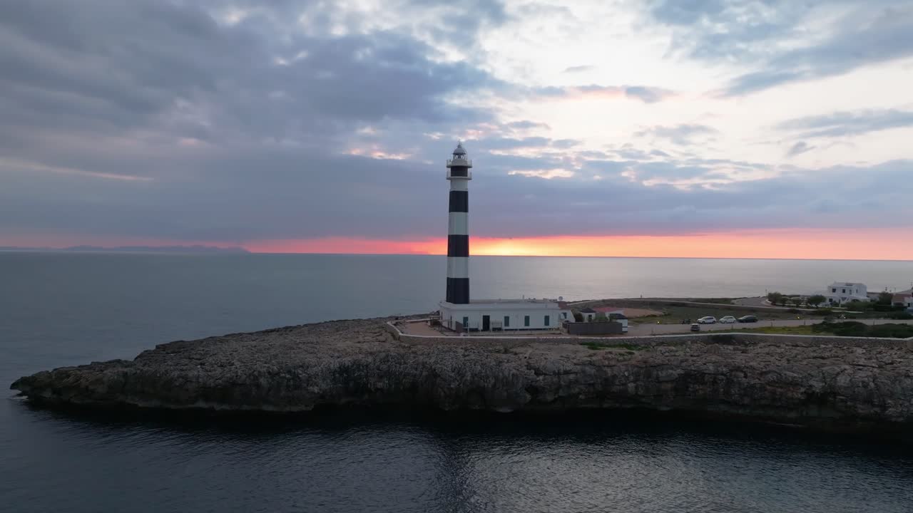 Aerial fly Cap d’Artrutx Lighthouse, Southwest Menorca landscape, ocean and city at dusk, sunset