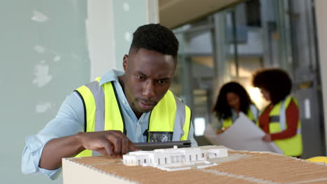 Casual-african-american-male-architect-looking-at-3d-model-in-office,-slow-motion,-copy-space