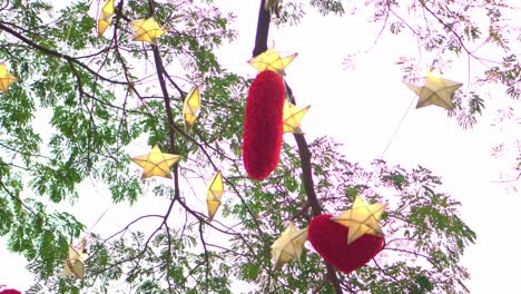 red hearts hanging on a tree with many paper stars and lights twinkling at night. valentine's day concept