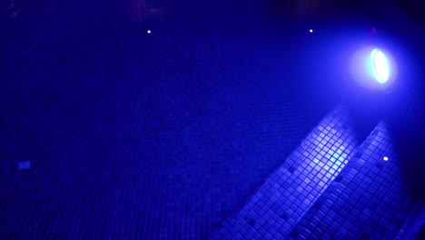 slow revealing shot of a indoor pool within a villa at night with blue led