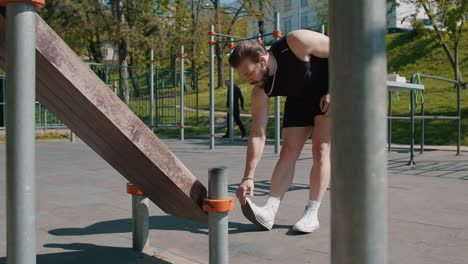 athletic man in sportswear stretching legs warm up body before cardio workout squatting exercises