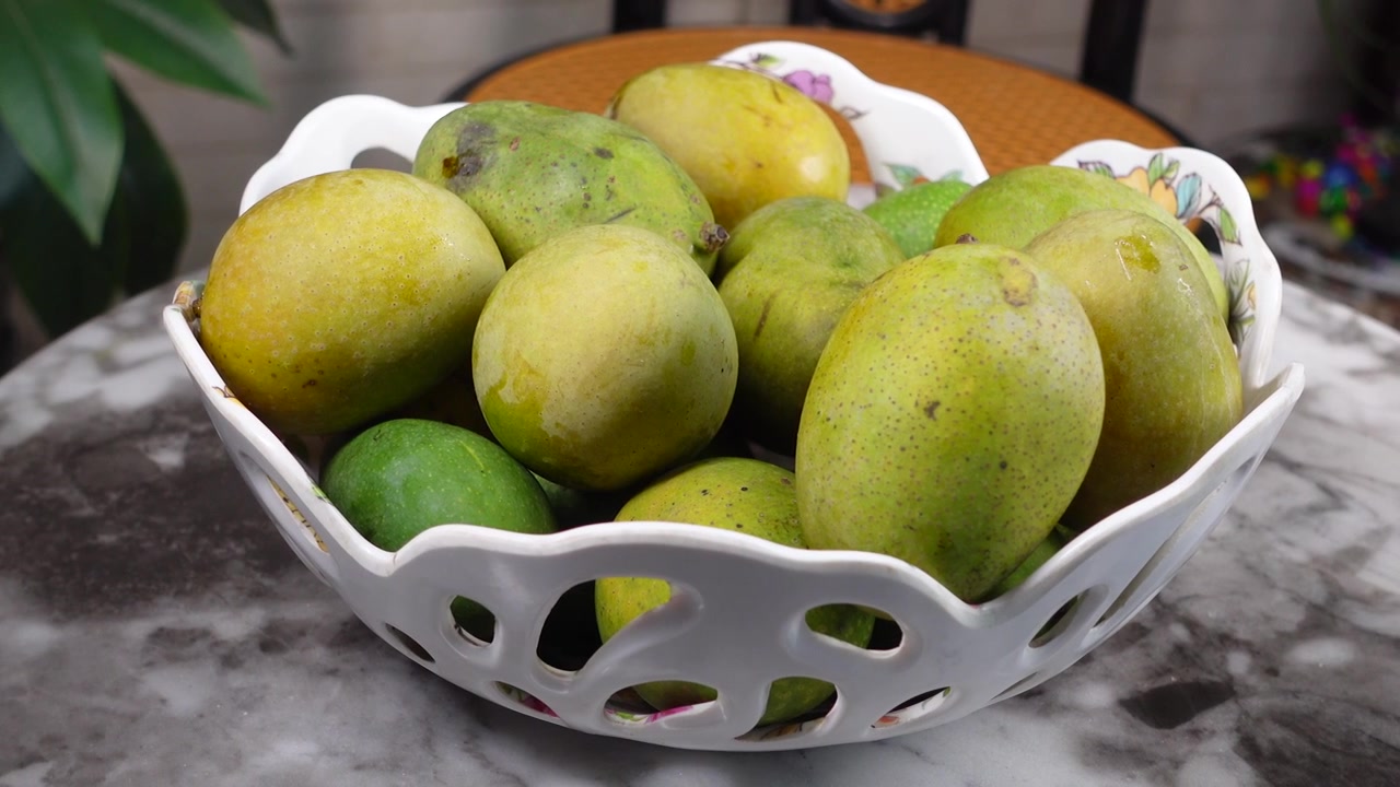 Manghi freschi verdi e gialli in una ciotola bianca