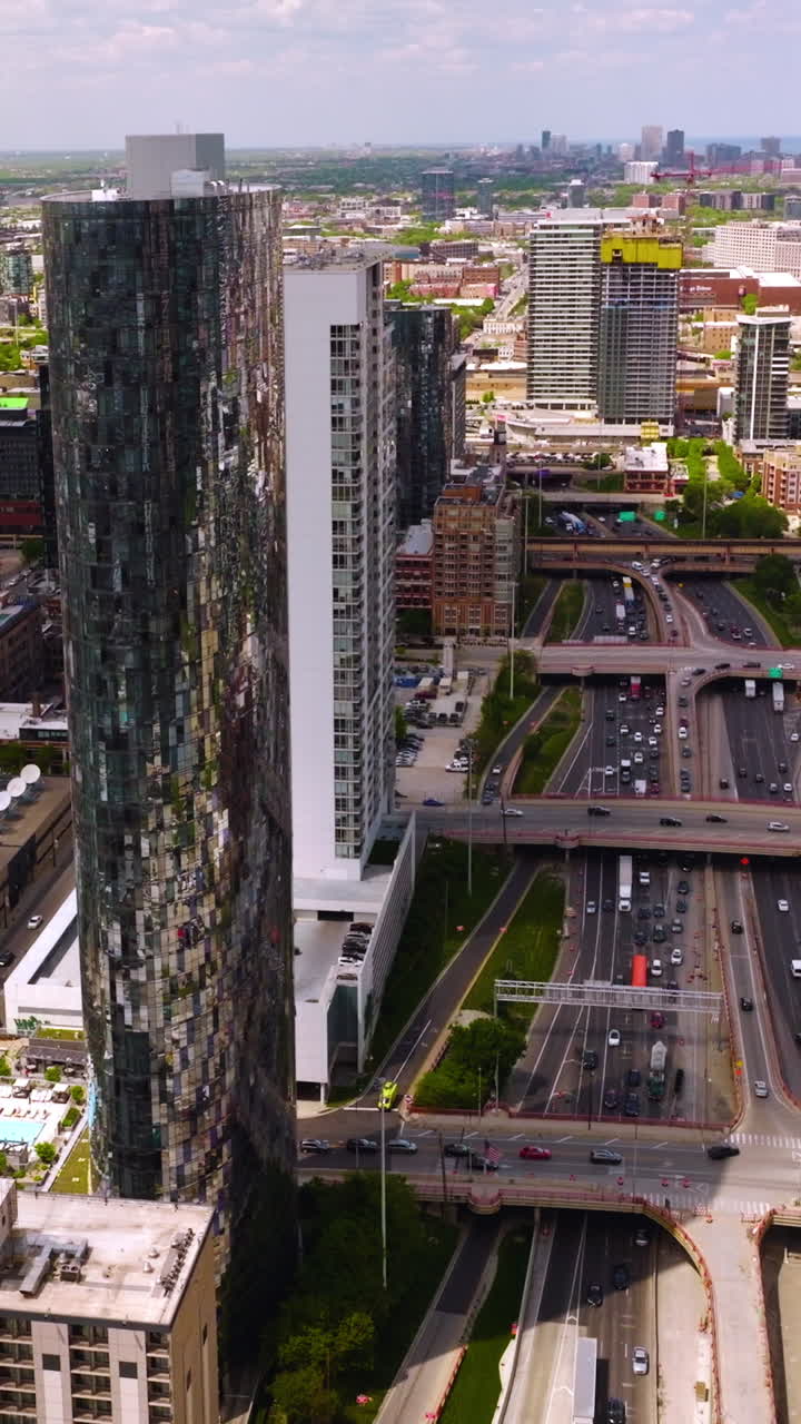 Stunning mirror skyscraper standing out from other buildings of Chicago, Illinois. Multi-lane road with numerous cars nearby. Vertical video