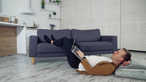 man using laptop at home. handsome man using laptop while lying on the floor