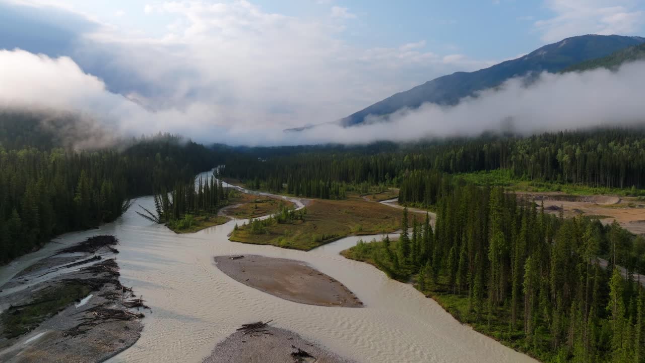 Panning drone shot of a cloudy valley over the Kicking Horse River looking into Yoho National Park in British Columbia Canada