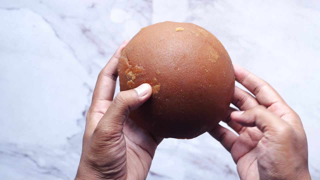 manos sosteniendo un pedazo de jaggery