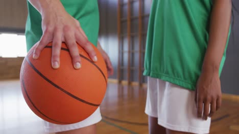 two diverse female basketball players wearing sportswear and holding ball