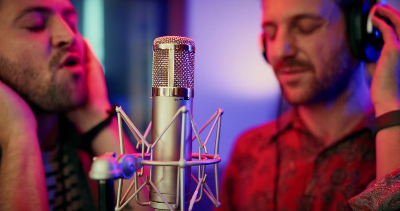 Due uomini che cantano in un microfono professionale in uno studio di registrazione