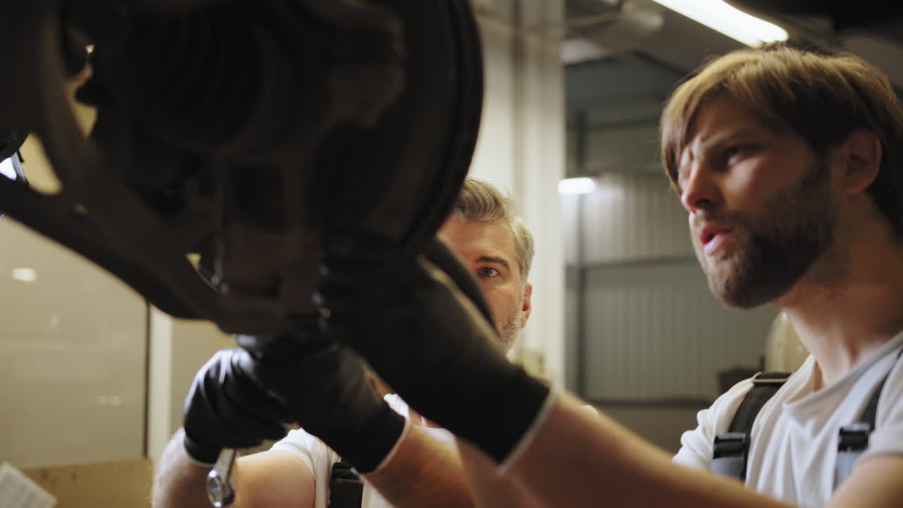 자동차의 서스펜션에 작업하는 두 명의 기계공