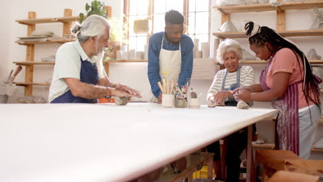 happy diverse group of potters shaping clay with hands in pottery studio
