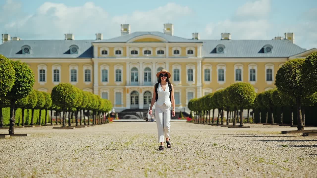 Woman strolls through Rundāle Palace garden on sunny day in Latvia countryside