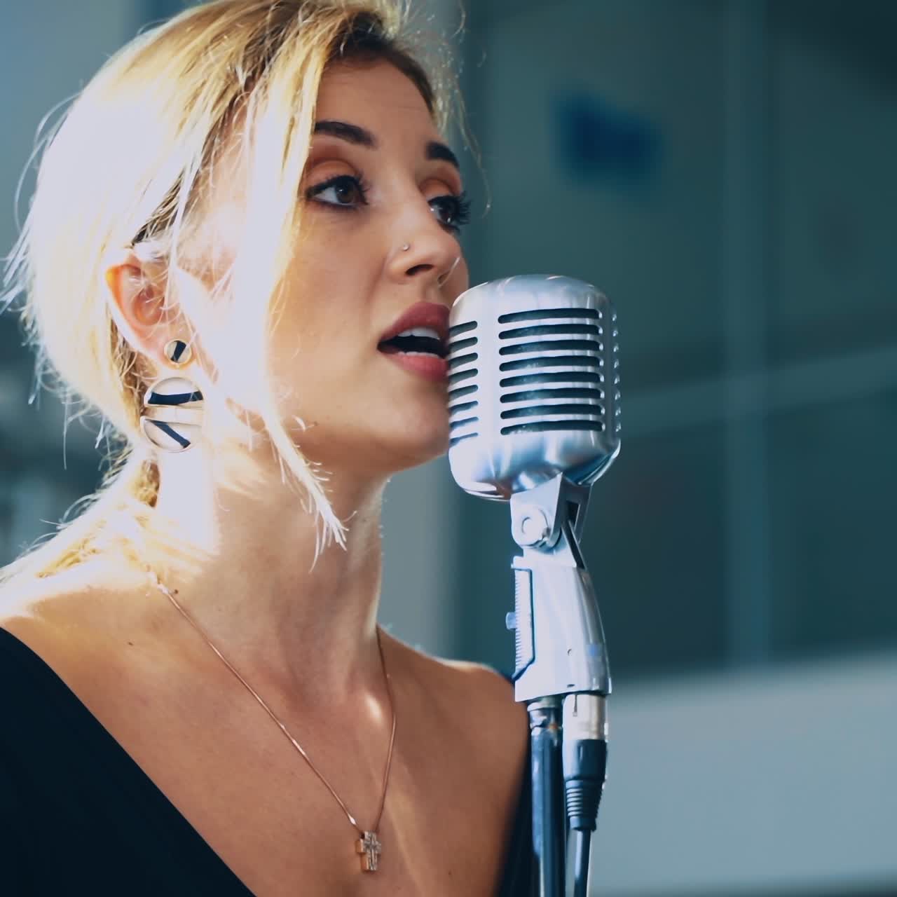 Blonde woman sings into the microphone. Attractive singer standing on the stage and singing a song. Musical entertainment.
