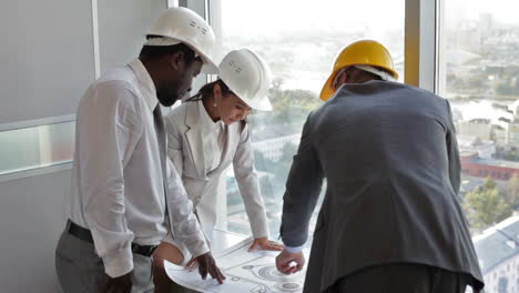 three architects looking at a blueprint in the office